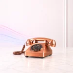 Vintage copper rotary telephone on a white table, representing the UK landline switch-off